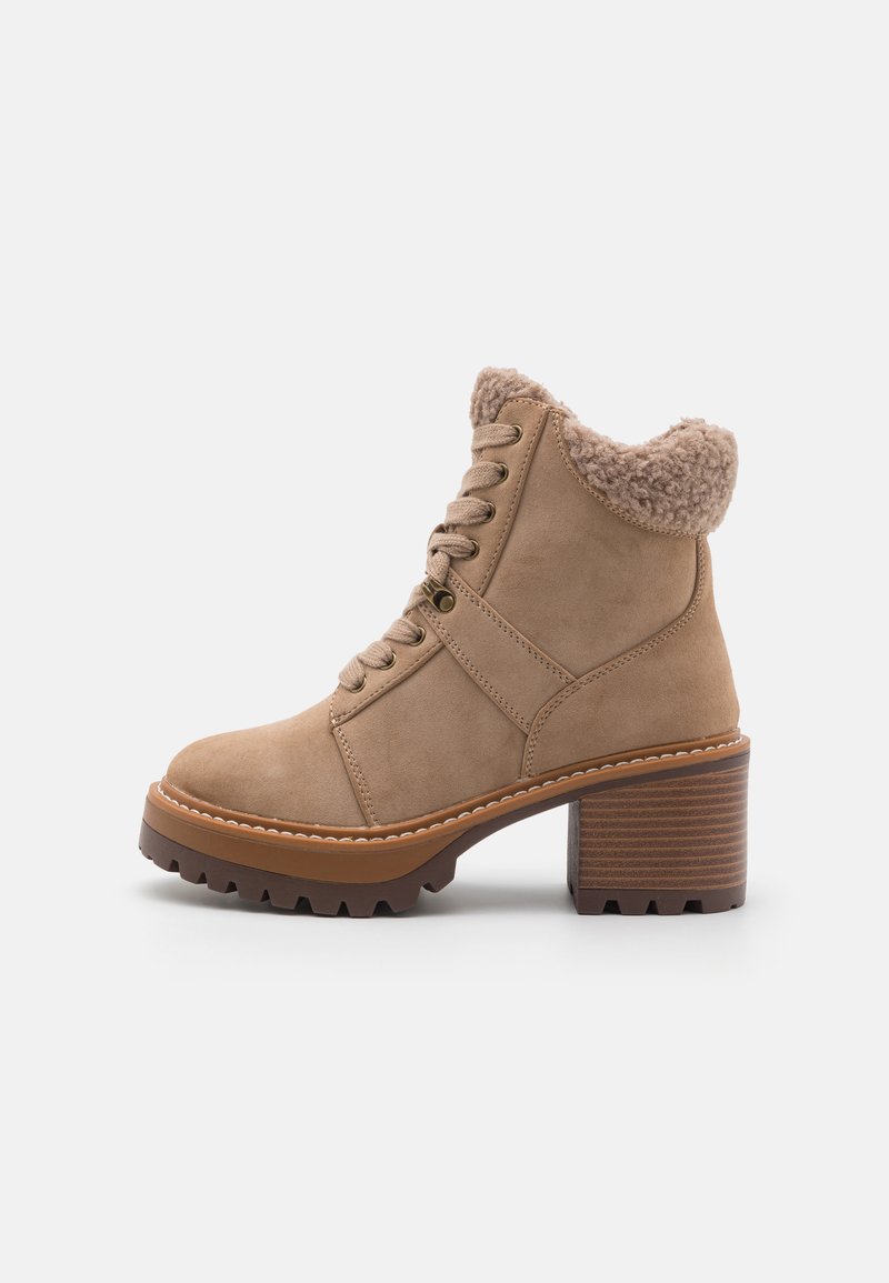 Tan suede ankle boot with a textured faux fur collar, lace-up design, and a brown chunky heel with visible grooves.