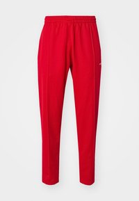 Röda, lätta träningsbyxor med elastisk midja, sidofickor och avsmalnande ben. Har en logotyp på framsidan till höger.