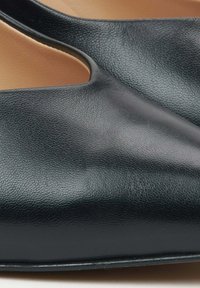 Zwarte leren schoen met een gladde textuur, met een uitsnijdontwerp aan de zijkanten voor een moderne uitstraling. Ronde neus en subtiele glans.