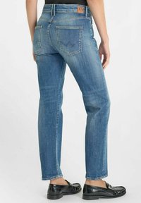 Lichtblauwe denim jeans met een rechte snit, voorzien van twee achterzakken en een tan kleurige taillebandlabel. Draag met zwarte instappers.