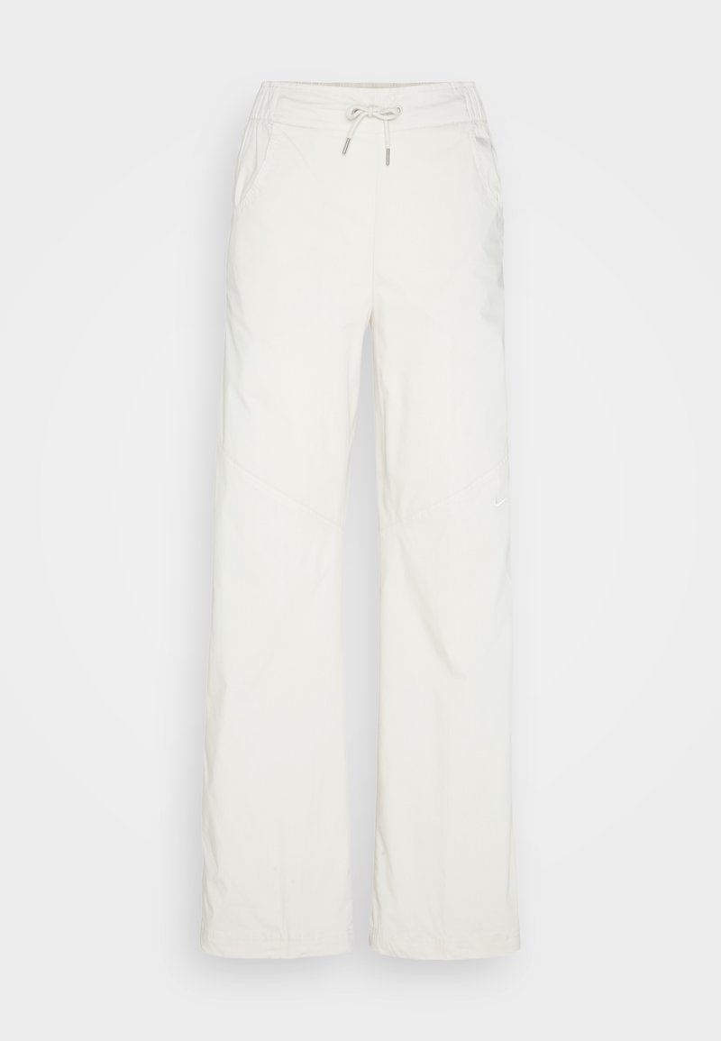 Weite Hosen aus hellem beige Stoff. Mit einem Kordelzugbund, zwei seitlichen Taschen und schrägen Nähten für zusätzliche Details.