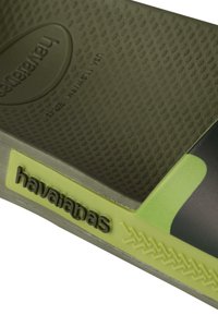 Infradito Havaianas verdi con suola in gomma testurizzata, dotate di logo rialzato e accento giallo sulla fascia con dettagli a zigzag.