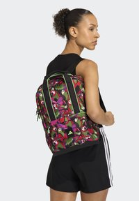 Zaino con un motivo vivace di uccelli colorati e fogliame, base nera, accenti verdi, più scomparti e spallacci imbottiti per il comfort.