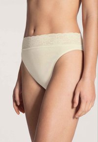 Beige Baumwollunterwäsche mit einem Spitzenbund, ausgestattet mit einem hohen Beinausschnitt und glatter Textur, ideal für Komfort und den alltäglichen Gebrauch.