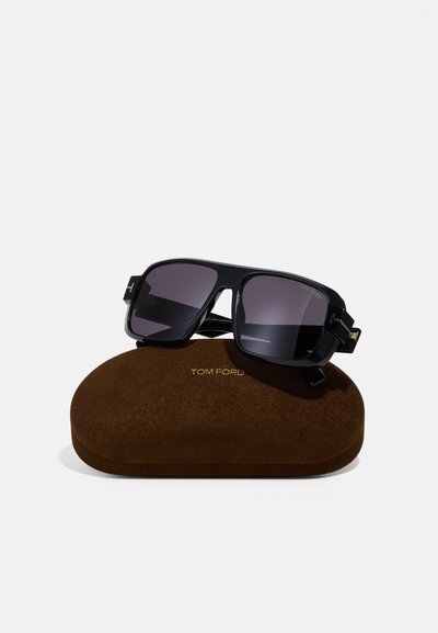 Černé acetátové sluneční brýle s tmavými skly, které mají čtvercový design. Součástí je hnědý semišový obal s embosovaným nápisem "TOM FORD" ve zlaté barvě.
