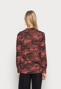 Camicia a maniche lunghe color ruggine con motivo marmorizzato nero, dotata di colletto e polsini con bottoni, realizzata in tessuto leggero.
