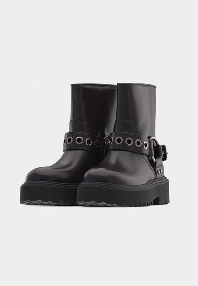 Μαύρα δερμάτινα μποτάκια έως τη μέση της γάμπας με παχιά ελαστικά πέλματα και διακοσμητικές λουράκια με μεταλλικά μεταλλικά πόρπες και λεπτομέρειες πόρπας.