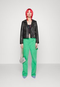 Svart läderjacka, kort svart topp med mönster, gröna vida byxor, silverväska, ljusblå klackar, rosa hår.