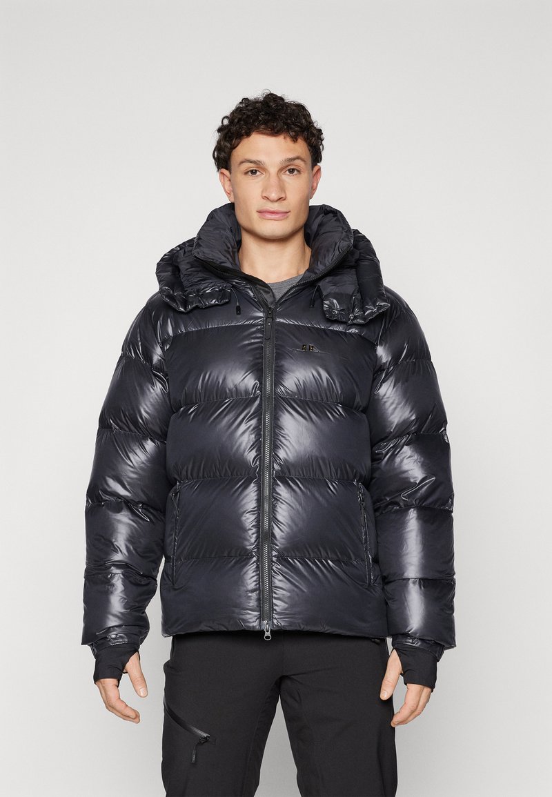 Must have puffer-jakk musta läikiva materjaliga, tikitud disain ja suur kapuuts. Omab eesmine tõmblukk ja elastsed mansetid soojuse tagamiseks.