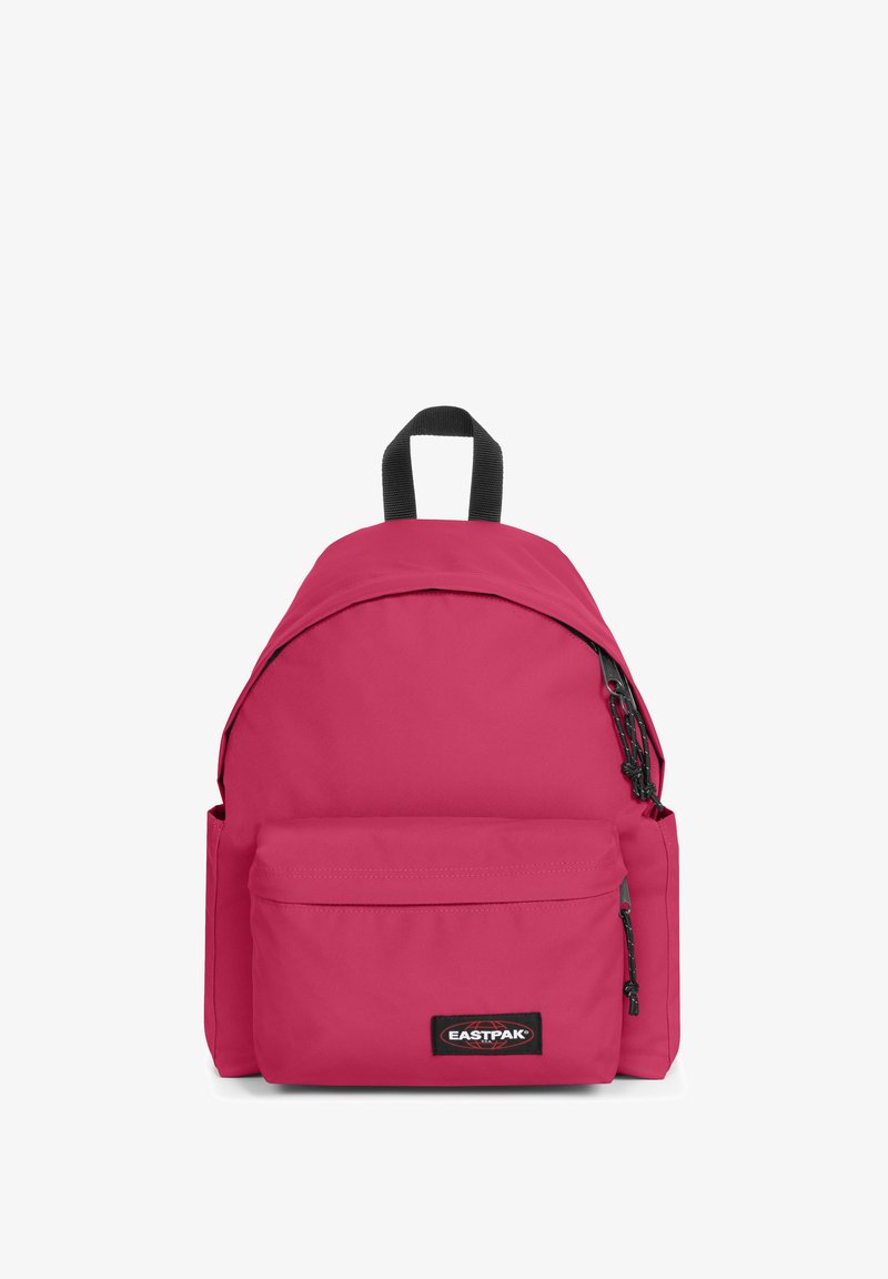 Růžový látkový batoh s zaobleným designem, přední kapsou a černými zipovými akcenty. Má horní ucho a nastavitelné ramenní popruhy.