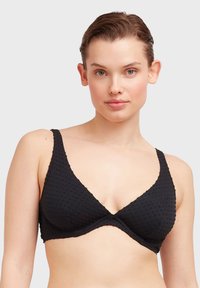Bralette a triangolo nero in tessuto testurizzato, con spalline larghe e una finitura liscia. Presenta un sottoseno di supporto e un design minimalista.