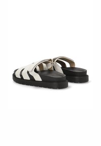 Sandalias blancas y negras con correas anchas, que presentan una parte superior de cuero suave, una plantilla acolchada y una suela de goma negra gruesa.