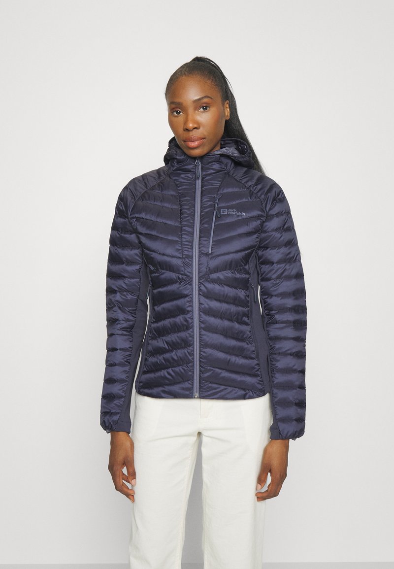 Veste matelassée navy avec capuche, présentant un design matelassé, une fermeture éclair à l'avant et un logo de marque sur la poitrine. Texture lisse et coupe ajustée.
