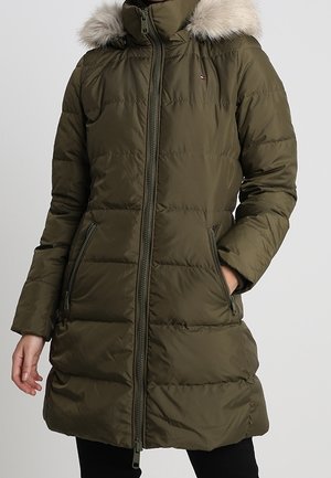 Oliivinvihreä tikattu pitkä talvitakki, jossa on vetoketju edessä, sivun vetoketjutaskut ja irrotettava huppu vaaleanharmaalla tekoturkisreunuksella.