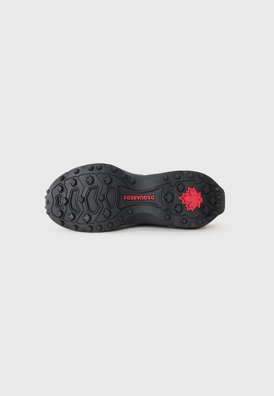 Black rubber shoe sole with textured tread, featuring red branded detail and star-shaped traction points for grip.