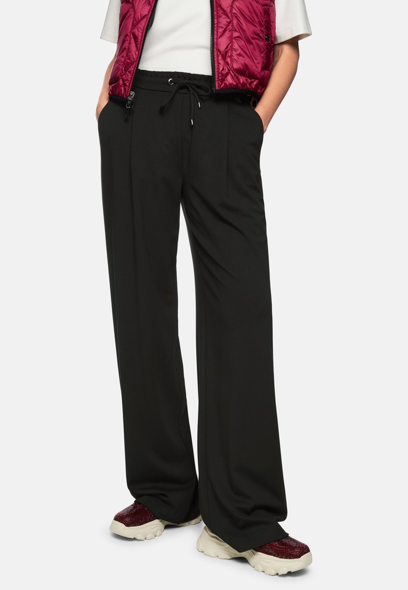 Black wide-leg pants with a relaxed fit, featuring an elastic waistband and drawstring. Worn with a white shirt and maroon vest.