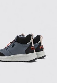 Baskets montantes en textile bleu et noir, avec une semelle grise mouchetée, des accents orange et des panneaux texturés noirs. Conception à lacets avec des tirettes.