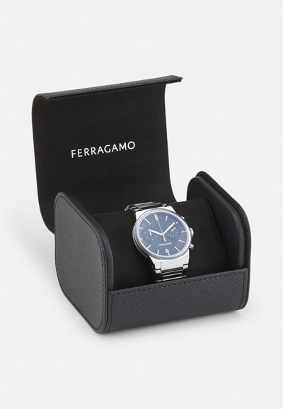 Ferragamo watch in a black fabric-lined case. Features a blue dial, stainless steel band, silver accents, and two chronograph sub-dials.