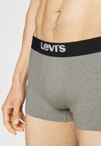 Harmaat puuvillabokserit mustalla joustovyötäröltä, jossa on valkoinen "Levi's"-logo. Sileä pinta ja istuva muotoilu.