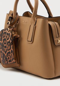 Skórzana torba w kolorze brązowym o strukturalnym kształcie; posiada kontrastującą kieszonkę w panterkę z złotymi detalami; gładka tekstura i podwójne uchwyty.