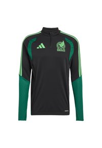 Hosszú ujjú fekete sportfelső zöld díszítéssel, cipzáras gallérral, csapatlogóval és texturált zöld ujjal.