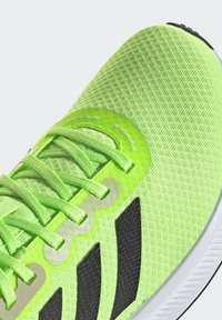 Scarpa sportiva verde neon con tomaia testurizzata, accenti neri e lacci tonali. Presenta un design leggero e un profilo suola imbottito.
