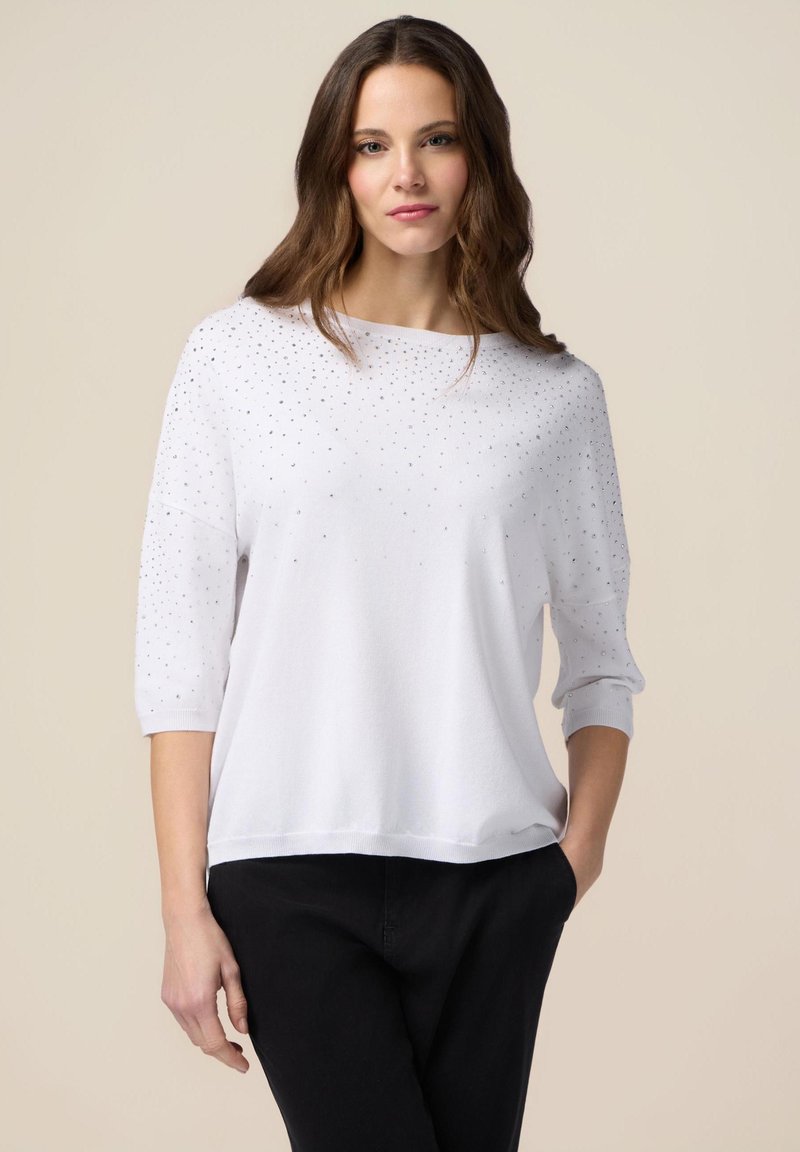 Maglione bianco con maniche a tre quarti, caratterizzato da un motivo a pois di strass, texture morbida e vestibilità comoda.