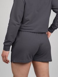Felpa grigia e pantaloni corti coordinati realizzati in un tessuto morbido. I pantaloni corti hanno una vestibilità comoda e fessure laterali; la felpa presenta maniche lunghe.