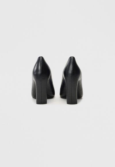 Zwarte leren hoge hakken met een尖尖neus en een chunky hak, voorzien van een gladde textuur en subtiele stikdetails aan de achterkant.