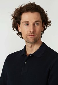 Námořnická polo tričko z texturované tkaniny, s tříknoflíkovou légou a límečkem. Tričko se nachází na lehce pihovatém tónu pleti.