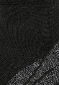 Calzini neri e grigi con un motivo a maglia testurizzato, con una parte superiore nera liscia che contrasta con la parte inferiore a strisce grigie.