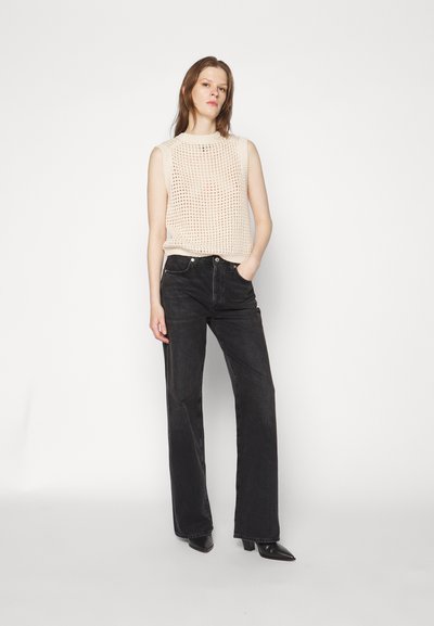 Knit beige sleeveless top with open weave pattern; paired with high-waisted black denim jeans, straight-leg cut, black pointed-toe shoes.