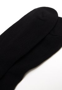 Calcetines negros hechos de un material acanalado con un diseño de punta sin costuras, que presentan una textura suave y un color uniforme en toda su extensión.