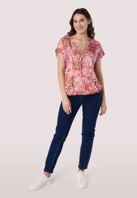 Roze bloezen top met korte mouwen, V-hals en geraffineerde details; gecombineerd met donkerblauwe skinny jeans en witte sneakers.