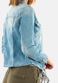 Ljusblå denimjacka med en klassisk design, med en bröstficka, knäppte ärmslut och en något kortad nederkant.