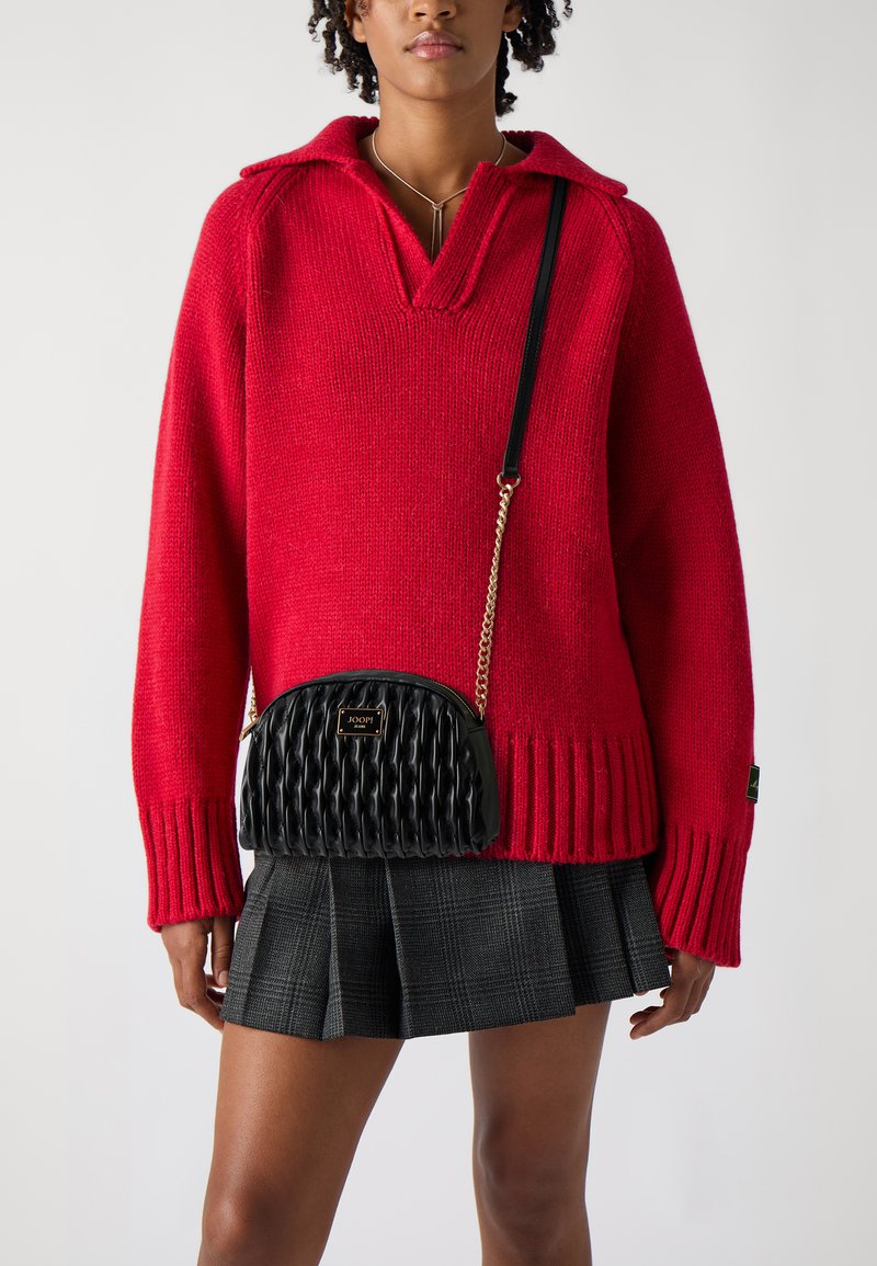 Maglione rosso a maglia con colletto, con polsini e orlo a coste. Borsa a tracolla nera imbottita con catena dorata. Gonna a quadri.