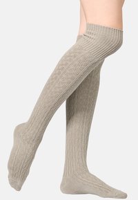 Chaussettes montantes en matériau beige texturé avec un motif côtelé et une section de pied unie, conçues pour le confort et un bon ajustement.