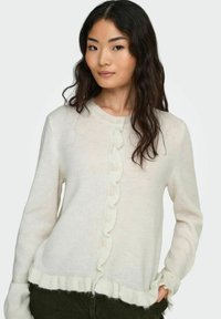 Cardigan crema chiaro con un davanti a onde, polsini e orlo inferiore a costine. Presenta bottoni lungo il centro e una finitura morbida e texture.