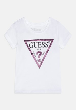 White short-sleeve T-shirt with purple triangular GUESS logo and text "GUESS U.S.A. Washed Jeans" on front.