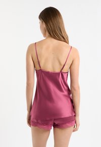 Satynowy zestaw piżamowy w głębokim różu, składający się z bezrękawnika i szortów. Szorty ozdobione koronkową lamówką na dole. Gładka faktura.
