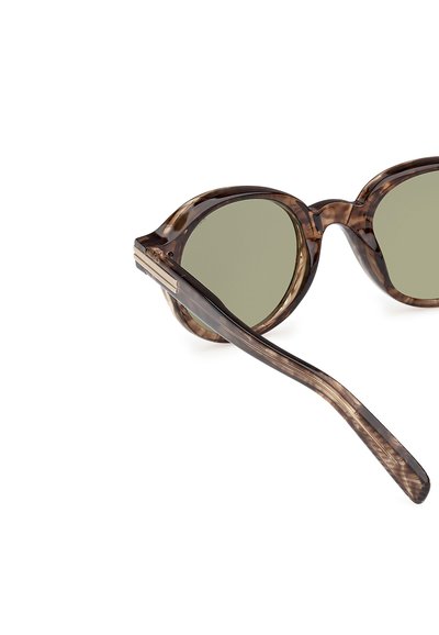Bruna sköldpaddsmönstrade solglasögon med gröna linser, rundade linser och en bred ramdesign. Glasögonbågarna har en slät yta.