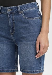 Denimshorts i mörkblått med rak passform, högt midjeband, framfickor och upprullad fåll, tillverkade av ett texturerat tyg.
