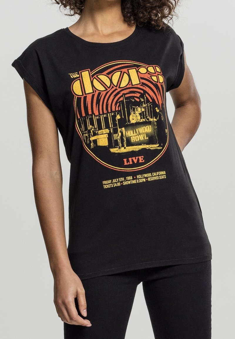 T-shirt en coton noir avec des manches roulées, présentant un imprimé vintage en jaune et rouge, évoquant un concert de 1968 au Hollywood Bowl.