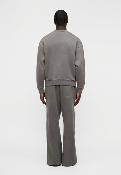 Γκρι φούτερ και παντελόνι με φαρδιά μπατζάκια από μαλακό, υφασμάτινο ύφασμα με υφή. Το σετ έχει μανσέτες με ριμπ υφή και λεπτομέρεια πίσω τσέπης.