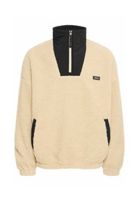 Fleece pullover in beige with a black zippered collar and side pockets, textured surface, and elastic cuffs for a snug fit.