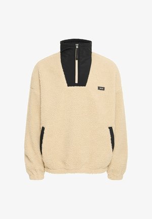 Beige fleece-pullover med svart dragkedja i kragen och sidofickor, texturerad yta och elastiska ärmslut för en tät passform.