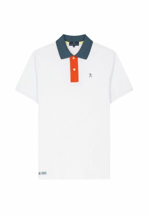 Polo blanco de manga corta con cuello azul verdoso oscuro, tapeta de botones naranja, pequeño logo de palas cruzadas en el pecho y texto cerca del dobladillo inferior.