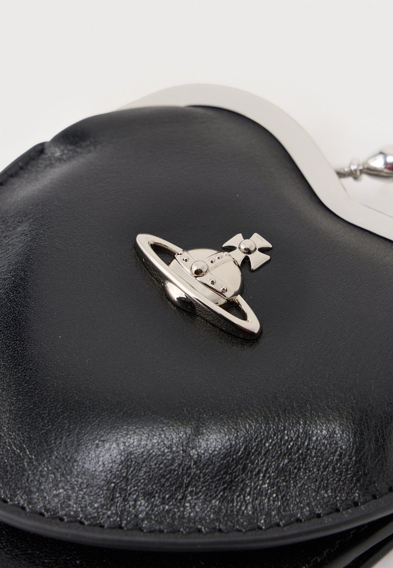 Porte-monnaie en cuir noir avec un emblème argenté en forme de planète, orné d'une croix au sommet et de détails en rivets.