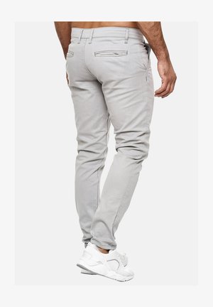Lichtgrijze slim-fit jeans gemaakt van een katoenmix, met twee achterzakken en stikseldetails, gecombineerd met witte sportschoenen.