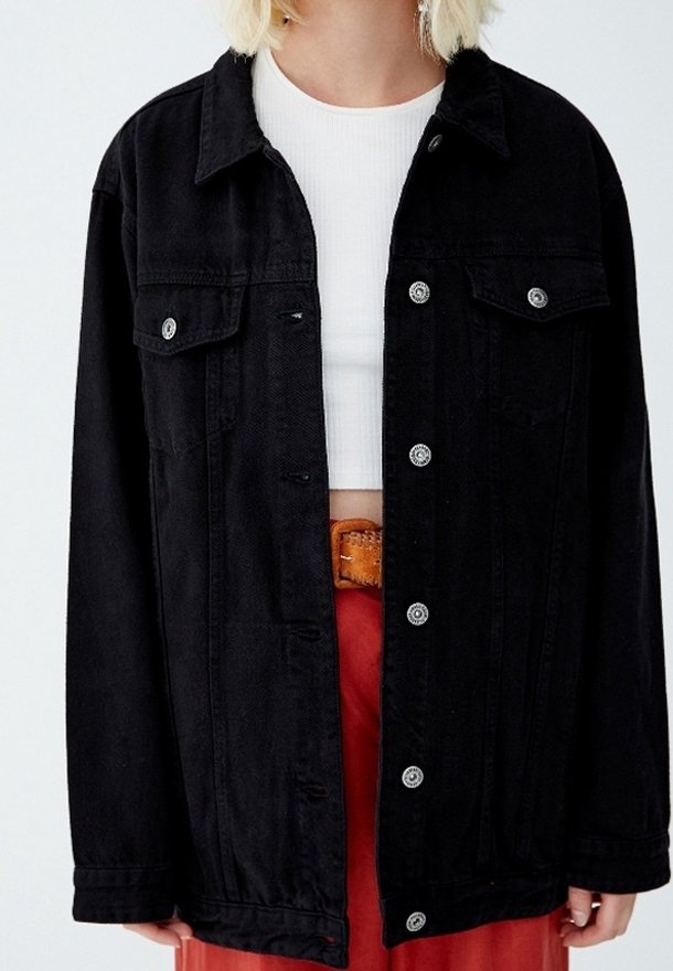 Schwarze Denimjacke mit durchgehender Knopfleiste, zwei Brusttaschen und silberner Hardware. Verfügt über einen lockeren Schnitt und lange Ärmel.